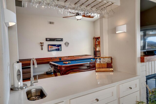 interior space featuring white cabinetry, pool table, a fireplace, and sink