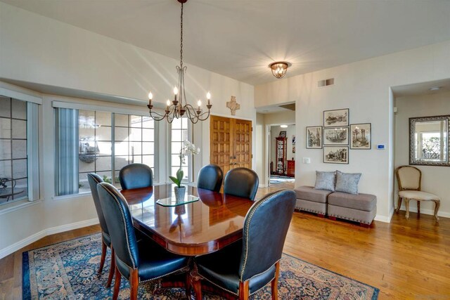 dining room featuring an inviting chandelier, hardwood / wood-style floors, and vaulted ceiling