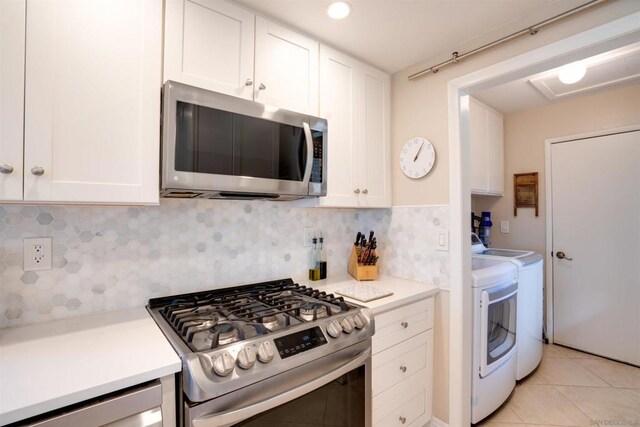 kitchen with appliances with stainless steel finishes, white cabinetry, decorative backsplash, light tile patterned floors, and independent washer and dryer