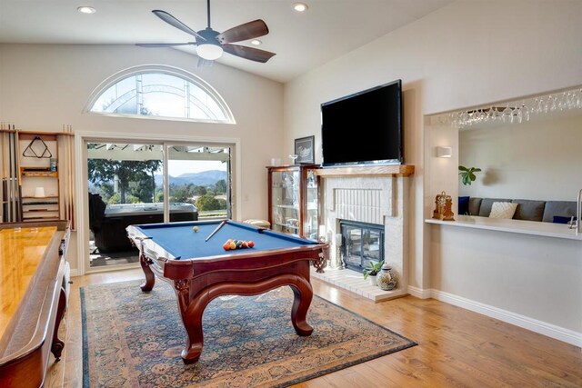 game room with lofted ceiling, pool table, a brick fireplace, light wood-type flooring, and ceiling fan