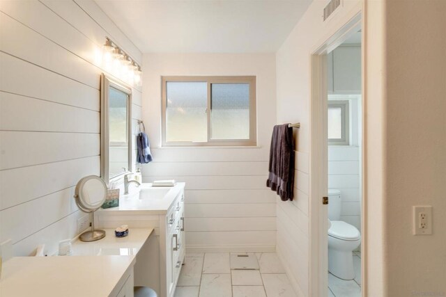 bathroom with wooden walls, vanity, and toilet