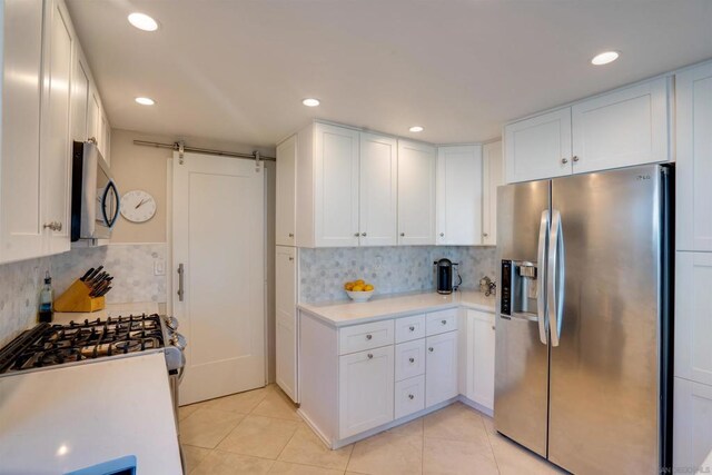 kitchen featuring white cabinetry, a barn door, and appliances with stainless steel finishes