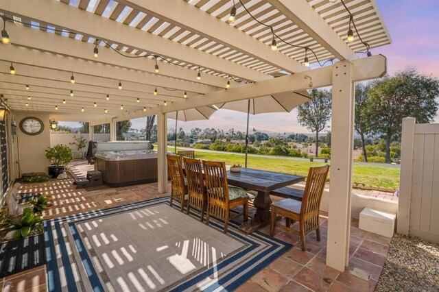 patio terrace at dusk with a hot tub, a lawn, and a pergola