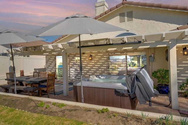 patio terrace at dusk with a pergola and a hot tub