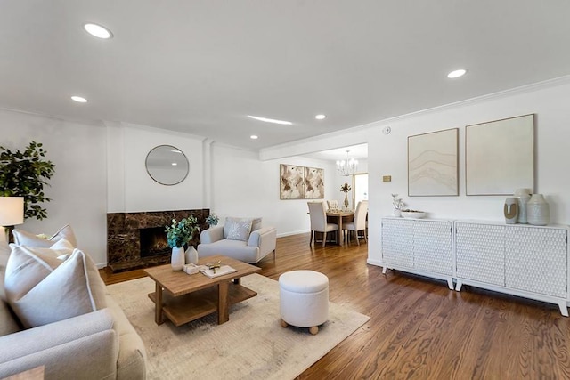 living room with an inviting chandelier, a fireplace, crown molding, and wood-type flooring