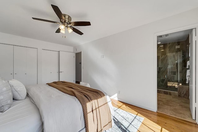 bedroom featuring wood-type flooring, connected bathroom, two closets, and ceiling fan