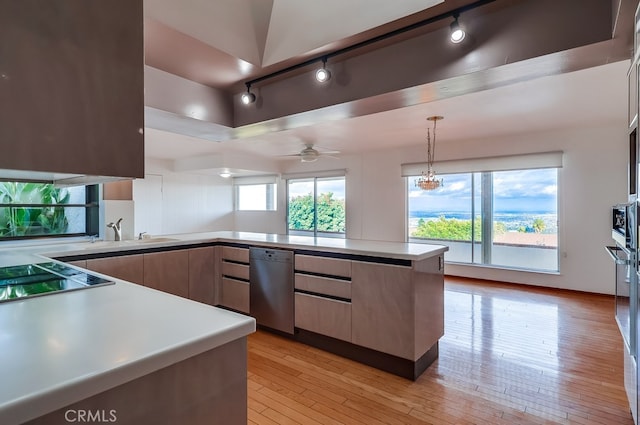 kitchen featuring sink, stovetop, dishwasher, hanging light fixtures, and light wood-type flooring