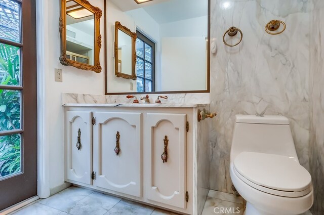 bathroom with vanity, toilet, tile patterned flooring, and tile walls