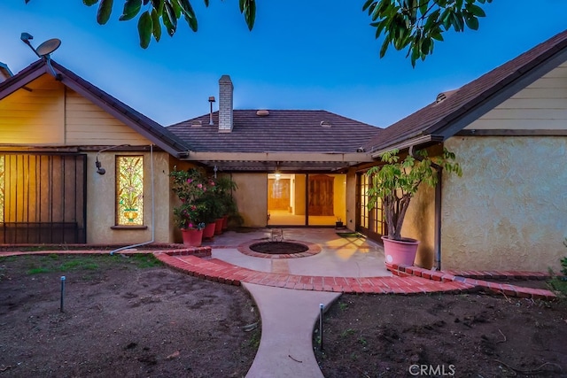 back house at dusk with a patio area