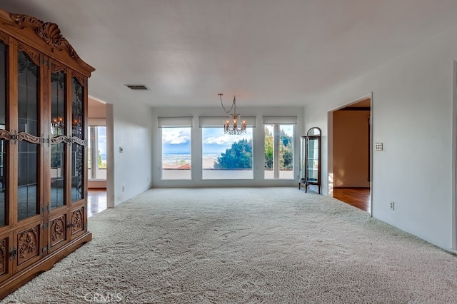 unfurnished living room featuring a chandelier and carpet flooring