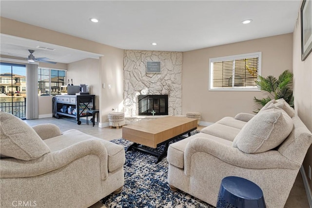 living room featuring a stone fireplace and ceiling fan