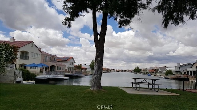 view of dock with a water view and a lawn