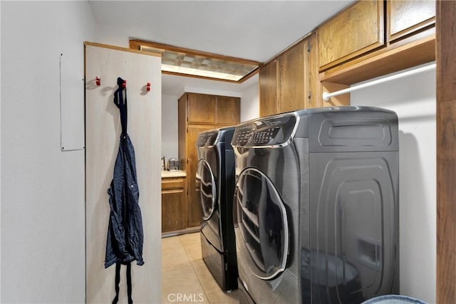 washroom with cabinets, sink, washer and dryer, and light tile patterned floors