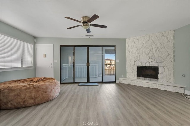 unfurnished living room with ceiling fan, a fireplace, and light hardwood / wood-style flooring