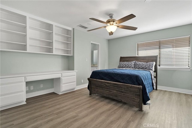 bedroom featuring built in desk, light hardwood / wood-style floors, and ceiling fan