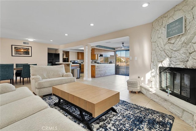 living room featuring light tile patterned floors and a stone fireplace