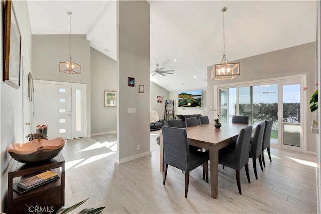 dining space featuring a chandelier, high vaulted ceiling, and light wood-type flooring