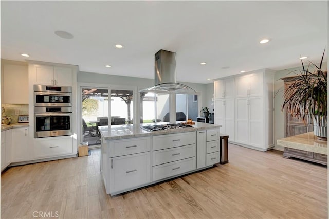 kitchen featuring white cabinetry, a center island, light hardwood / wood-style flooring, appliances with stainless steel finishes, and island exhaust hood