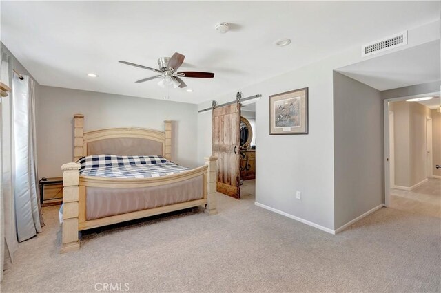 carpeted bedroom with a barn door and ceiling fan