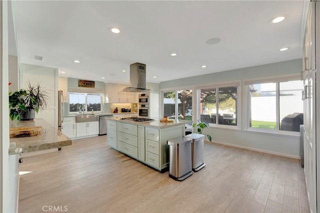 kitchen featuring a kitchen island, white cabinetry, island exhaust hood, light hardwood / wood-style floors, and stainless steel appliances