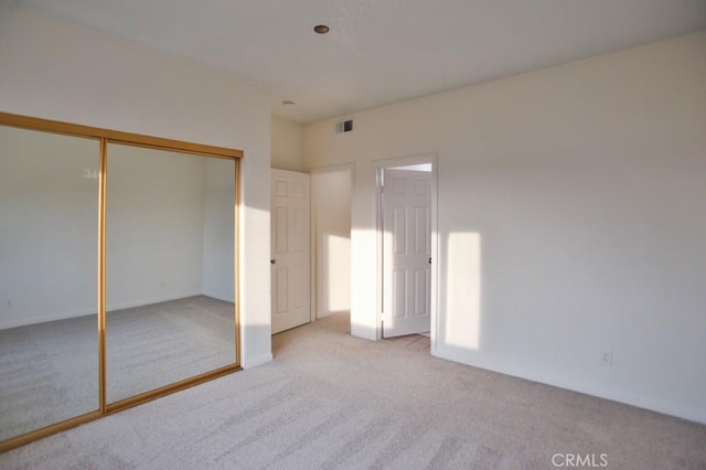 unfurnished bedroom featuring light carpet and a closet