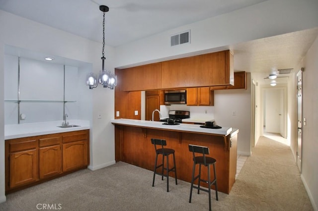 kitchen with hanging light fixtures, light colored carpet, stainless steel appliances, and kitchen peninsula