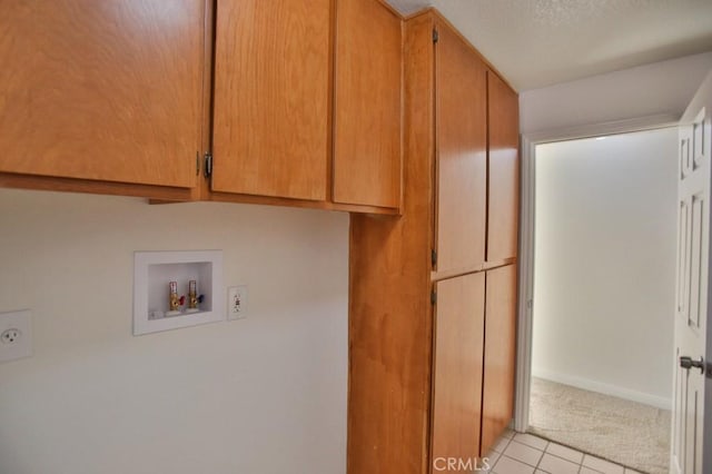 laundry room with cabinets, a textured ceiling, light tile patterned floors, electric dryer hookup, and washer hookup