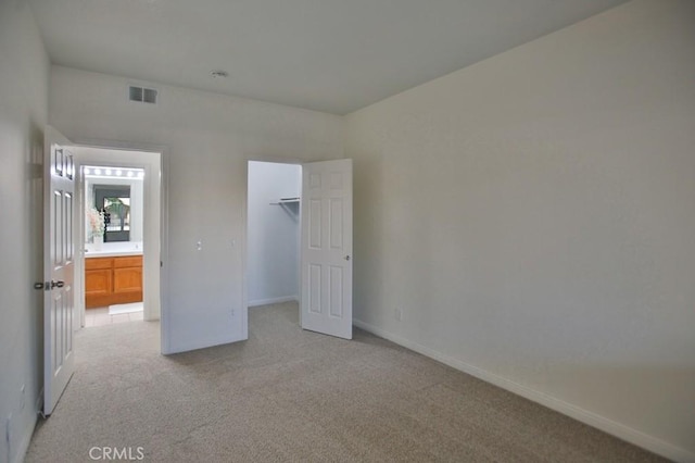 unfurnished bedroom with light colored carpet and a closet