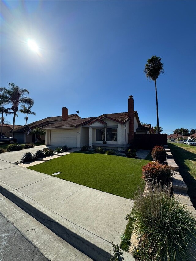 ranch-style home with a garage and a front lawn