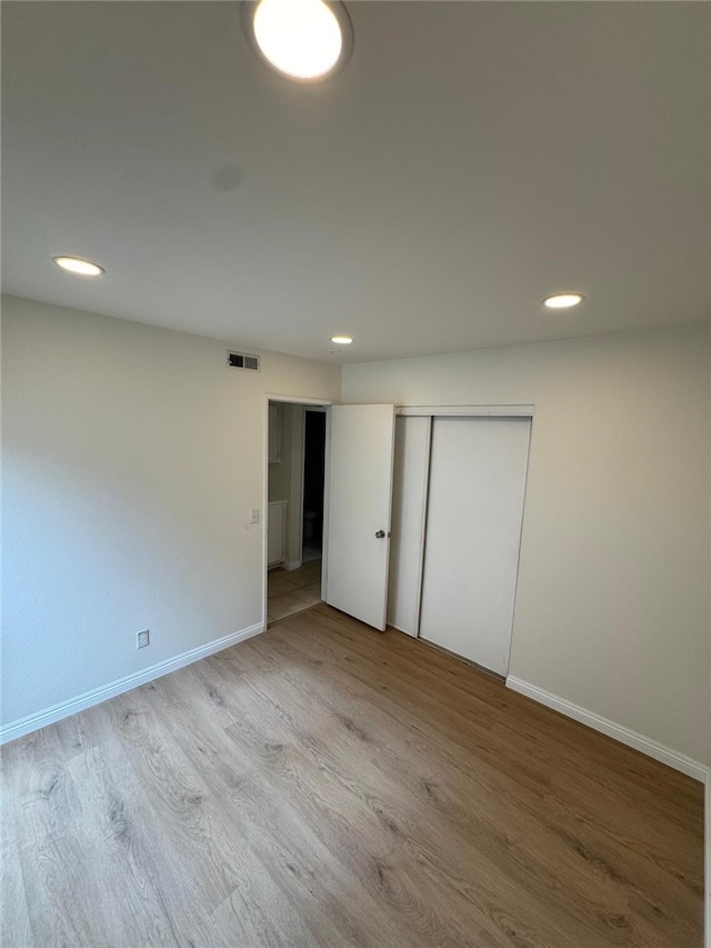 unfurnished bedroom with light hardwood / wood-style floors and a closet