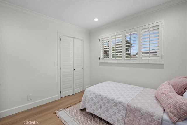 bedroom with ornamental molding, light wood-type flooring, and a closet