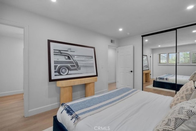 bedroom with light hardwood / wood-style floors and a closet