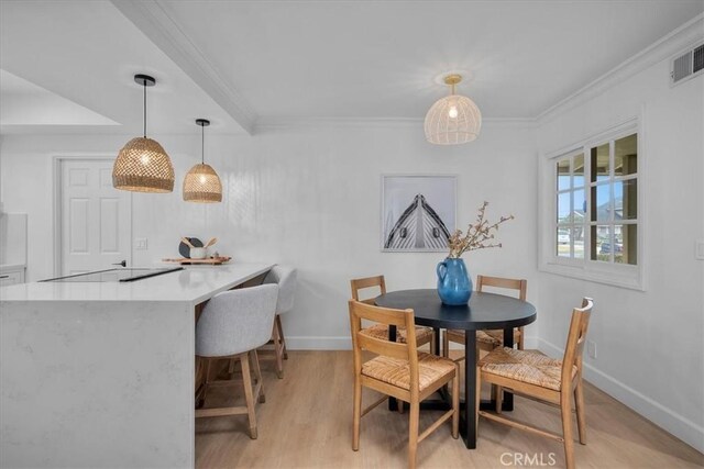 dining room featuring crown molding and light hardwood / wood-style flooring