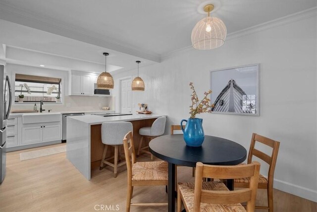 kitchen with a breakfast bar, sink, hanging light fixtures, appliances with stainless steel finishes, and white cabinets