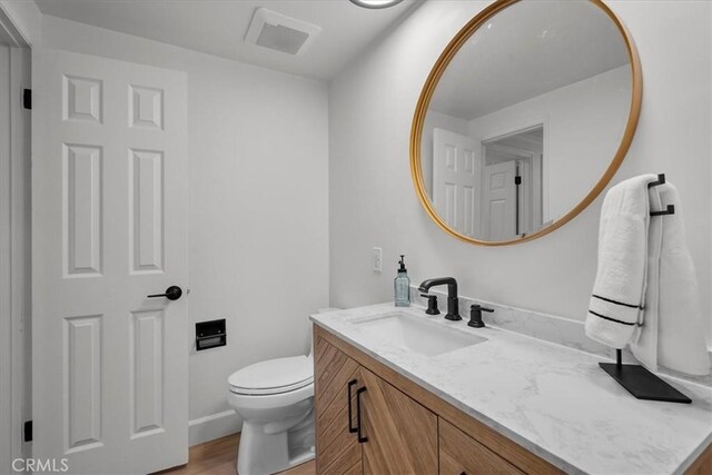 bathroom with vanity, wood-type flooring, and toilet