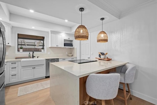 kitchen with a breakfast bar, pendant lighting, white cabinetry, dishwasher, and sink