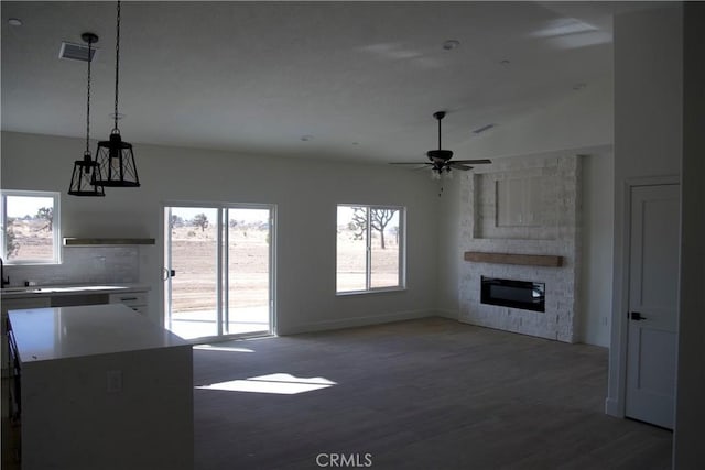 unfurnished living room featuring dark hardwood / wood-style flooring, a fireplace, lofted ceiling, and ceiling fan