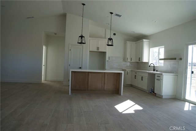 kitchen featuring sink, light wood-type flooring, white cabinets, and a kitchen island