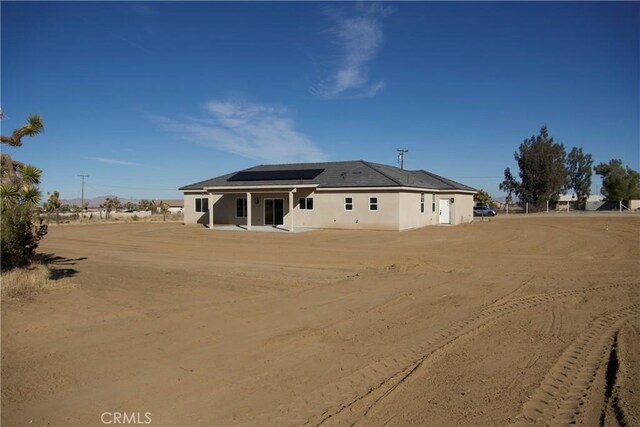 back of house featuring solar panels