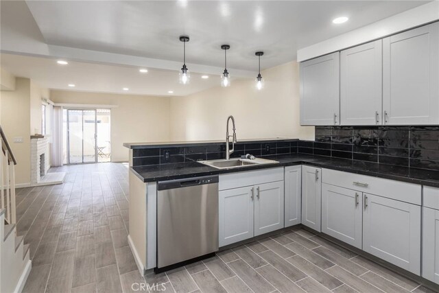 kitchen featuring sink, tasteful backsplash, hanging light fixtures, stainless steel dishwasher, and kitchen peninsula