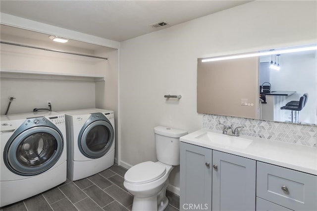 interior space with vanity, backsplash, independent washer and dryer, and toilet