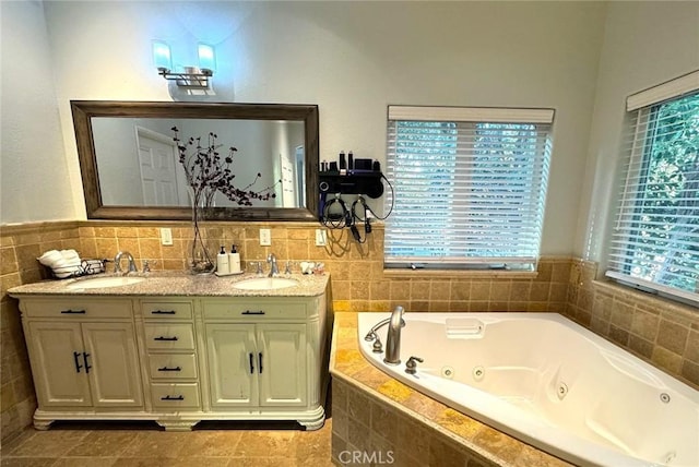 bathroom featuring a relaxing tiled tub, vanity, and a healthy amount of sunlight