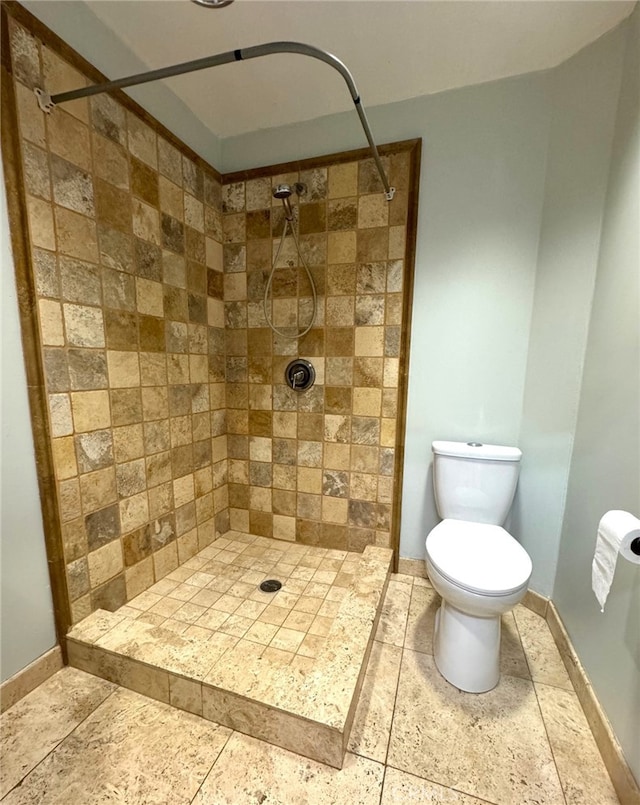 bathroom featuring a tile shower and toilet