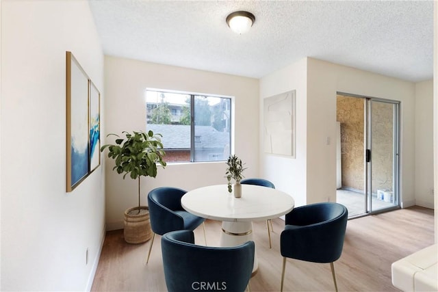 dining space with a textured ceiling and light wood-type flooring