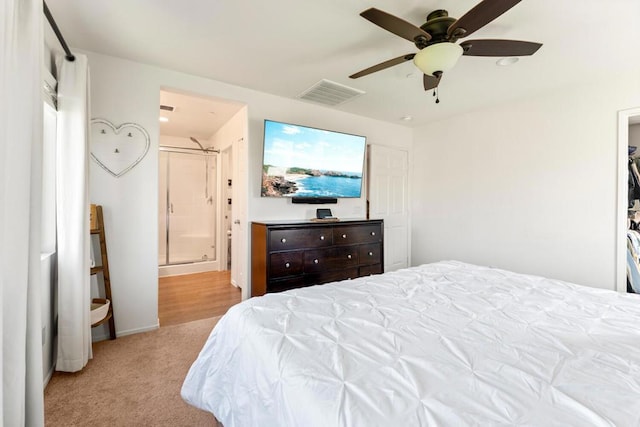 carpeted bedroom with ensuite bathroom and ceiling fan