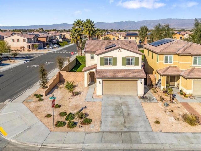 mediterranean / spanish-style home featuring a garage, a mountain view, and solar panels