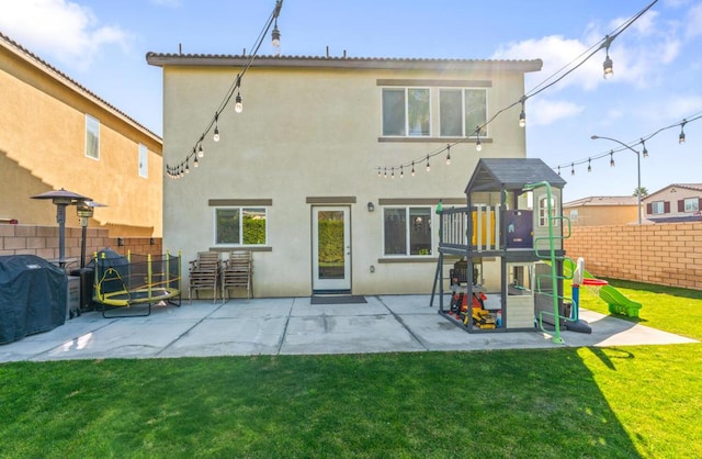 back of house with a yard, a patio, and a playground