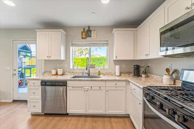 kitchen with sink, light hardwood / wood-style floors, white cabinets, and appliances with stainless steel finishes