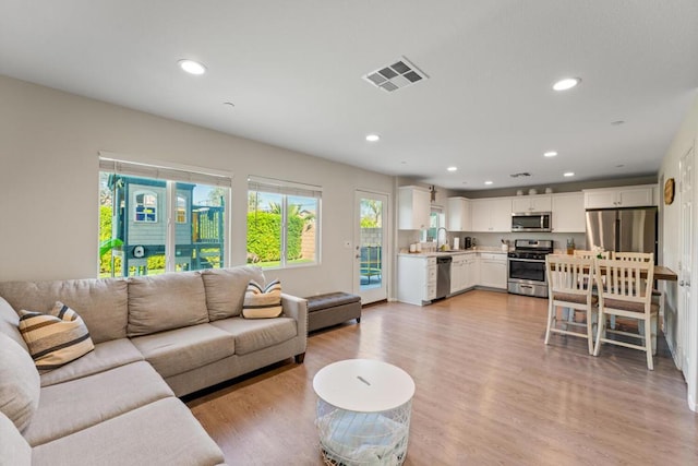 living room featuring sink and light hardwood / wood-style flooring