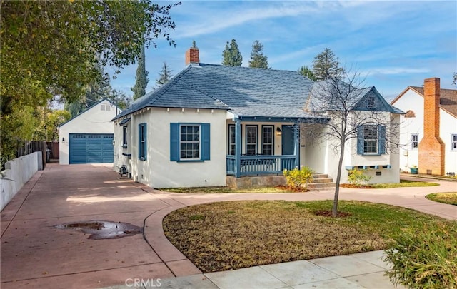 bungalow featuring an outbuilding, a garage, a front yard, and a porch